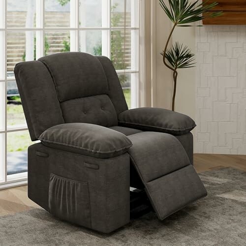 Gray recliner chair in a living room setting near large windows.